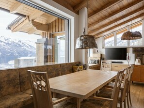 A modern kitchen with a large window, wooden ceiling, and a dining area with a table and chairs. - Apartment in Mittersill With Swimming Pool (Mittersill)