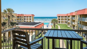 Un balcone con vista su una spiaggia, una piscina e un edificio con numerosi balconi.