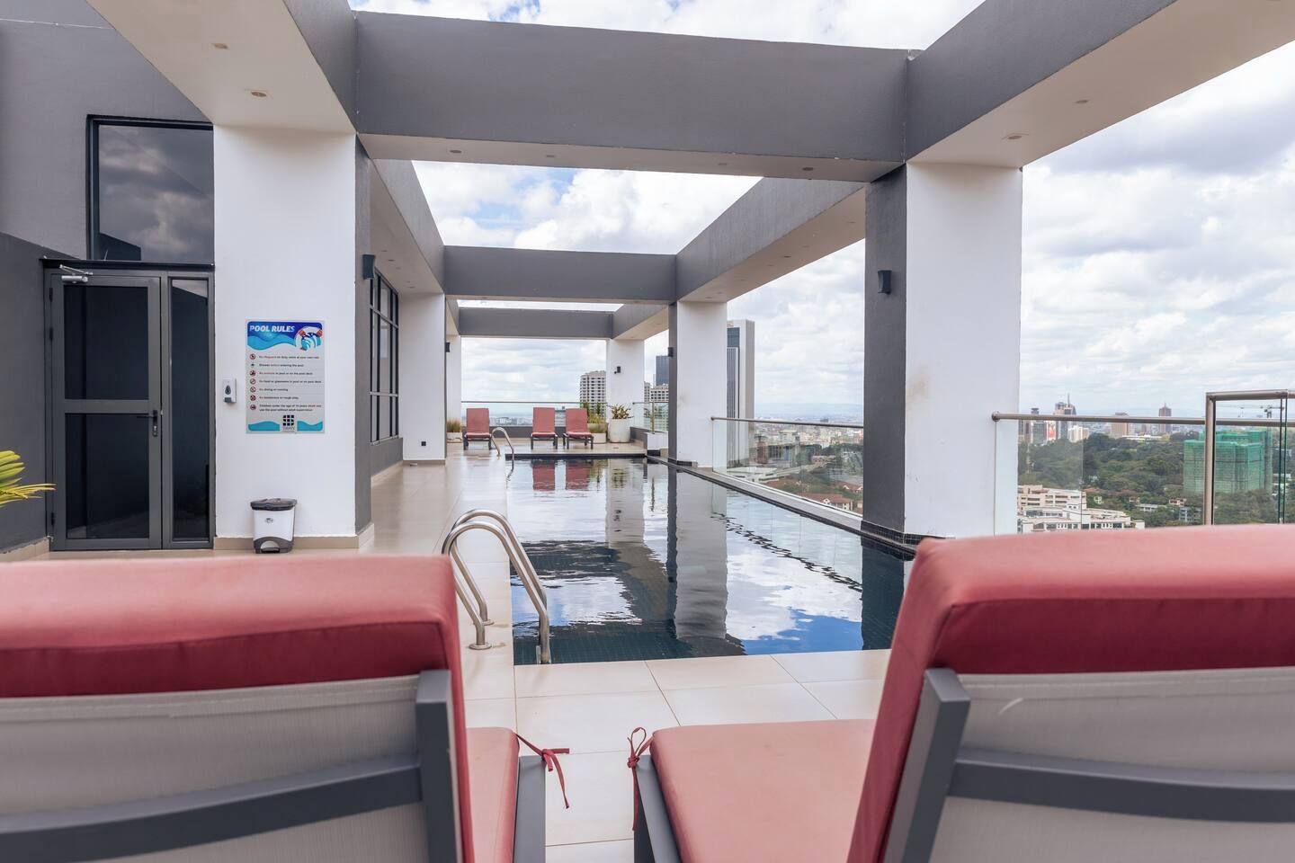 A rooftop pool area with lounge chairs, a pool, and a city view.