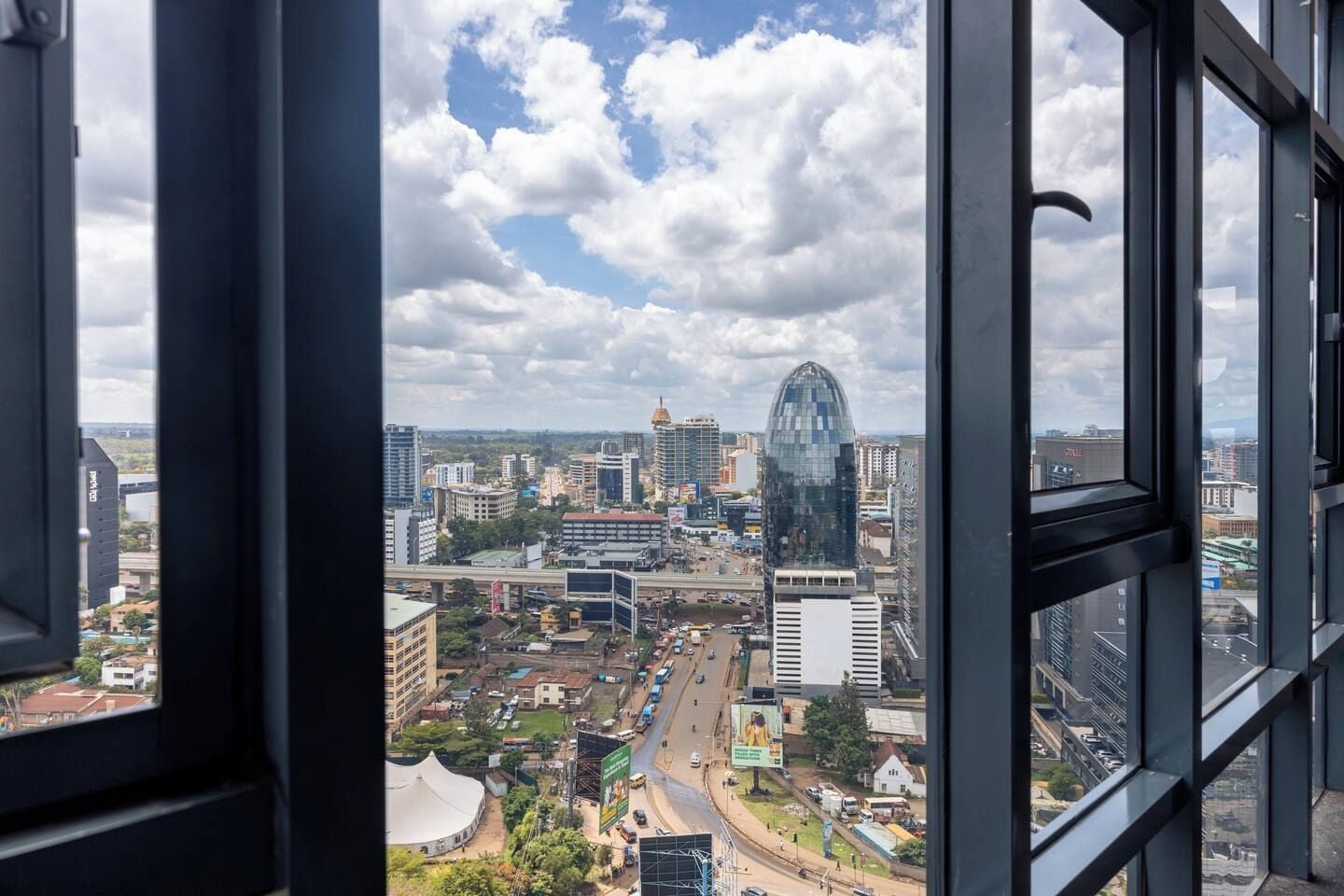 A cityscape viewed from a high-rise building with a clear sky and clouds.