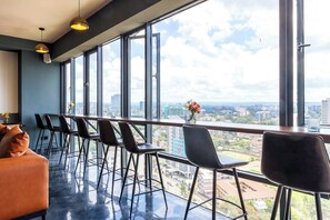 A modern bar area with a city view, large windows, and a seating arrangement. - Luxury 2-Bed Flat w/ Rooftop Pool & Gym (Nairobi)