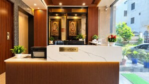 A reception desk with a marble top, wooden paneling, and a view of the outside. - Shree Radhe Shyam Palace (Khatoo)