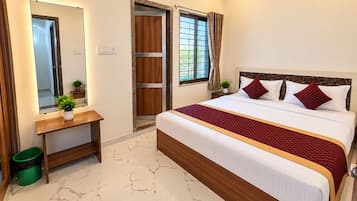 A hotel room with a bed, a mirror, a wooden door, and a window with curtains.