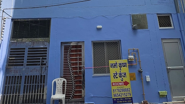 A multi-story building with a blue facade, multiple windows, and a signboard advertising rooms. - Namo Krishn Stay Kunj (Mathura)