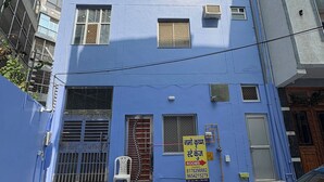 A multi-story building with a blue facade, a visible staircase leading to the entrance, and a parked car in front. - Namo Krishn Stay Kunj (Mathura)