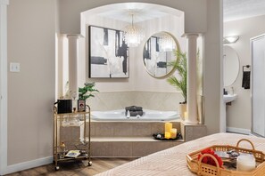 Ein modernes Badezimmer mit einer freistehenden Badewanne, einem großen Spiegel und einem Kronleuchter.
