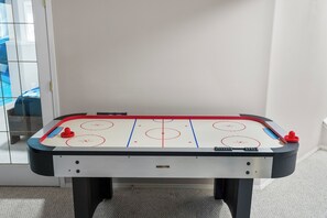 A foosball table with a white playing surface and red and blue goal areas.