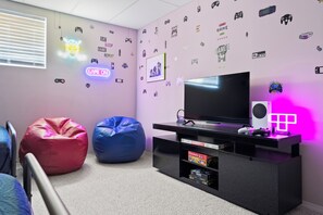 Ein Zimmer mit Fernseher, Sitzsäcken und Wandbildern zum Thema Gaming.