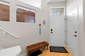 A hallway with a bench, a white door, and a window with a view of a wooden structure. - Drop the gloves, then soak it off. A hockey house with a game room (pinball, air hockey & projector), a jacuzzi spa suite & a private backyard with deck, BBQ & fire table. 12 min to River Cree Casino, 14 min to WEM. A weekend your crew won't forget. (Edmonton)