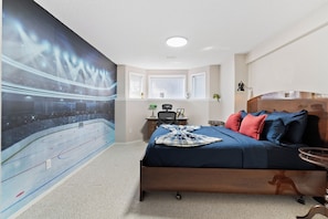 A bedroom with a bed, a desk, and a large wall mural.