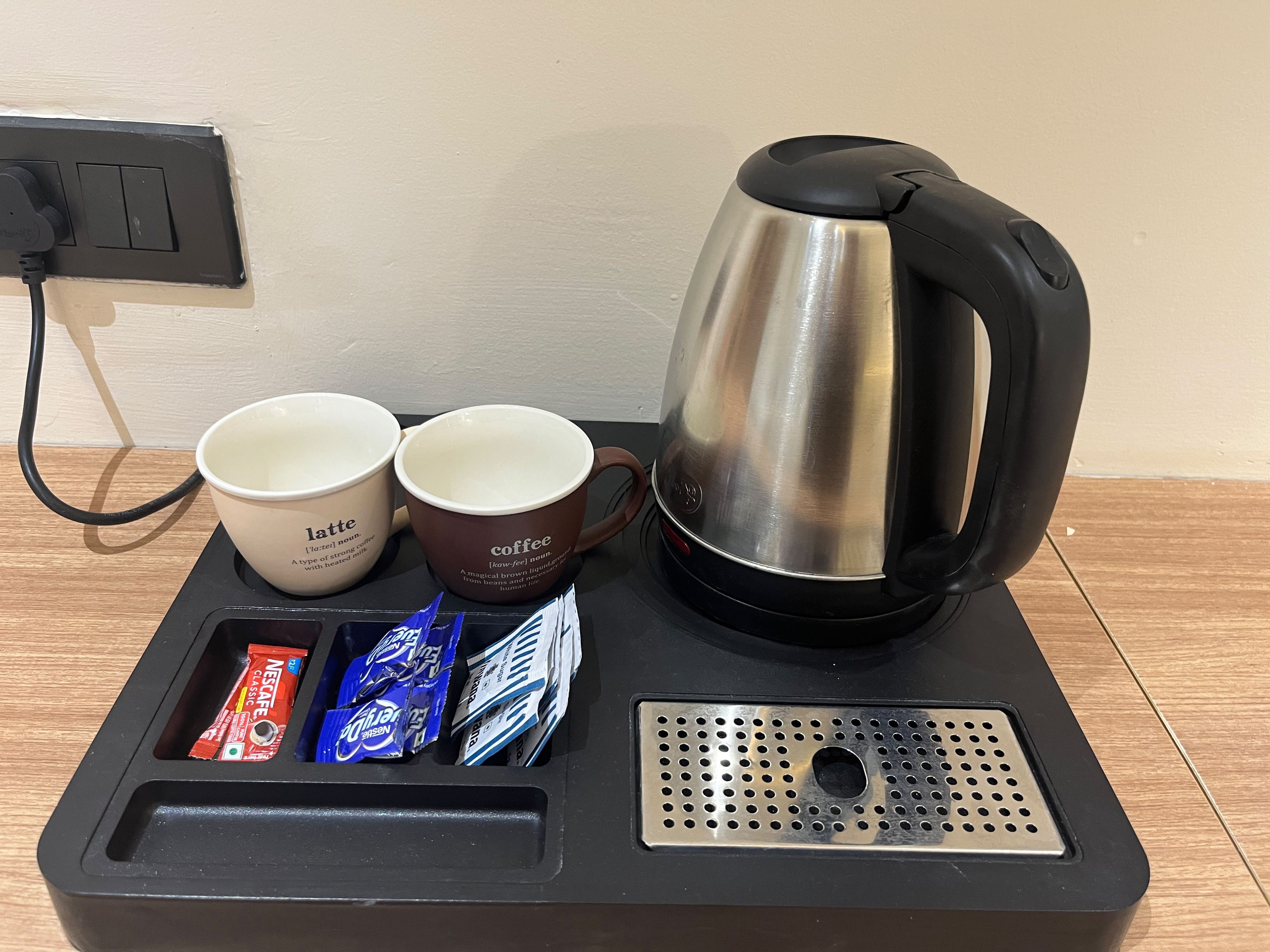 Une machine à café, deux tasses et un plateau avec des dosettes de café.