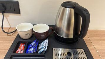 Une machine à café, deux tasses et un plateau avec des dosettes de café.