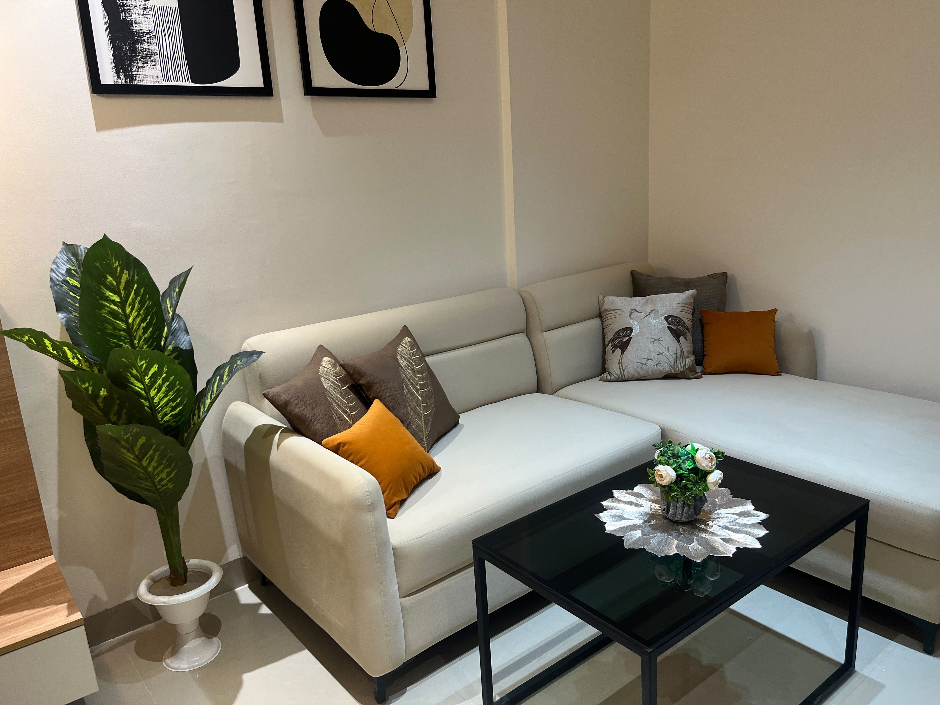 Un salon moderne avec un canapé, des coussins décoratifs, une table basse et des  œuvres d’art murales.