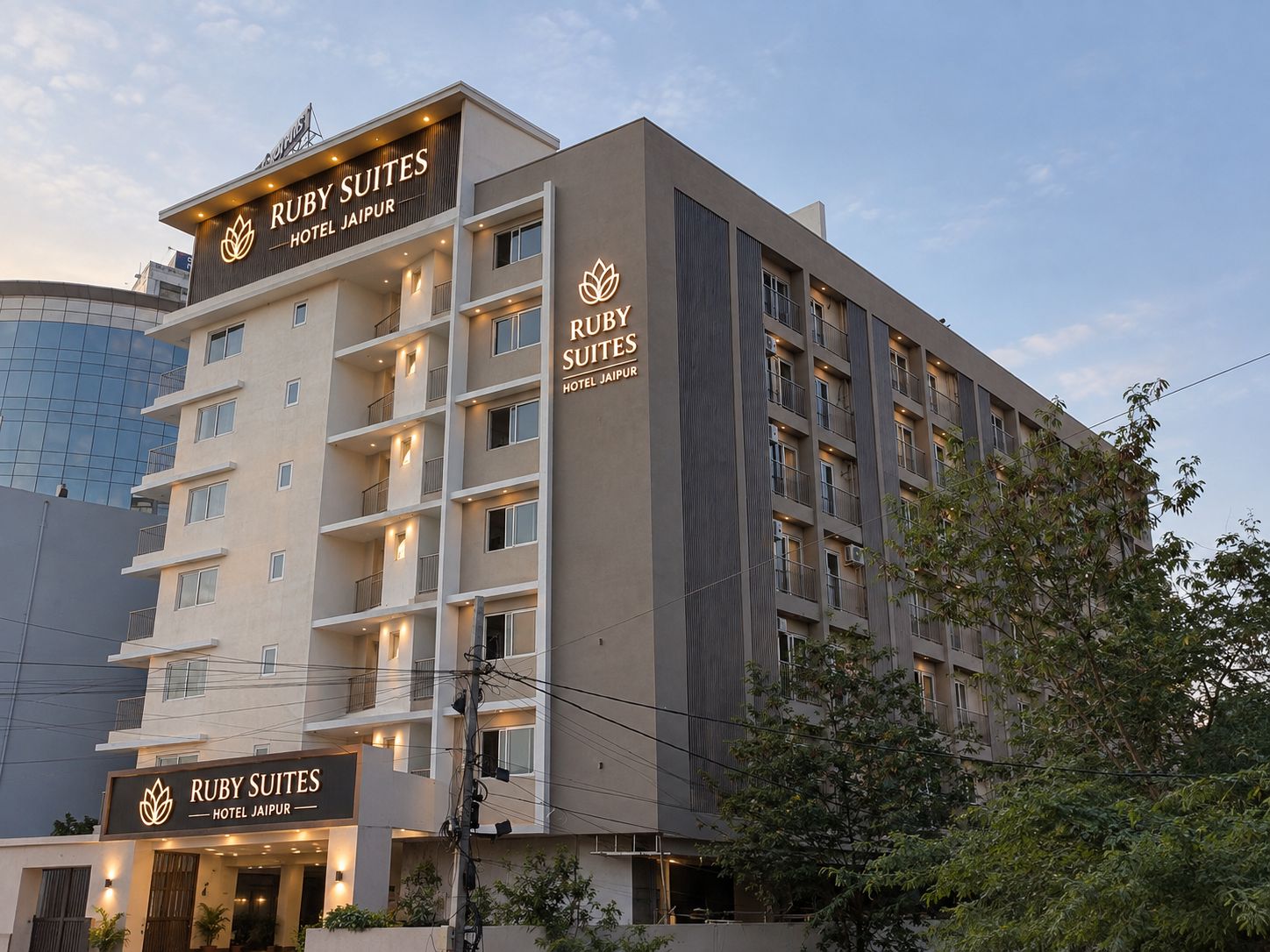 Un immeuble hôtelier à plusieurs étages, doté de balcons et d’une enseigne indiquant « Ruby Suites Hotel Jaipur ».