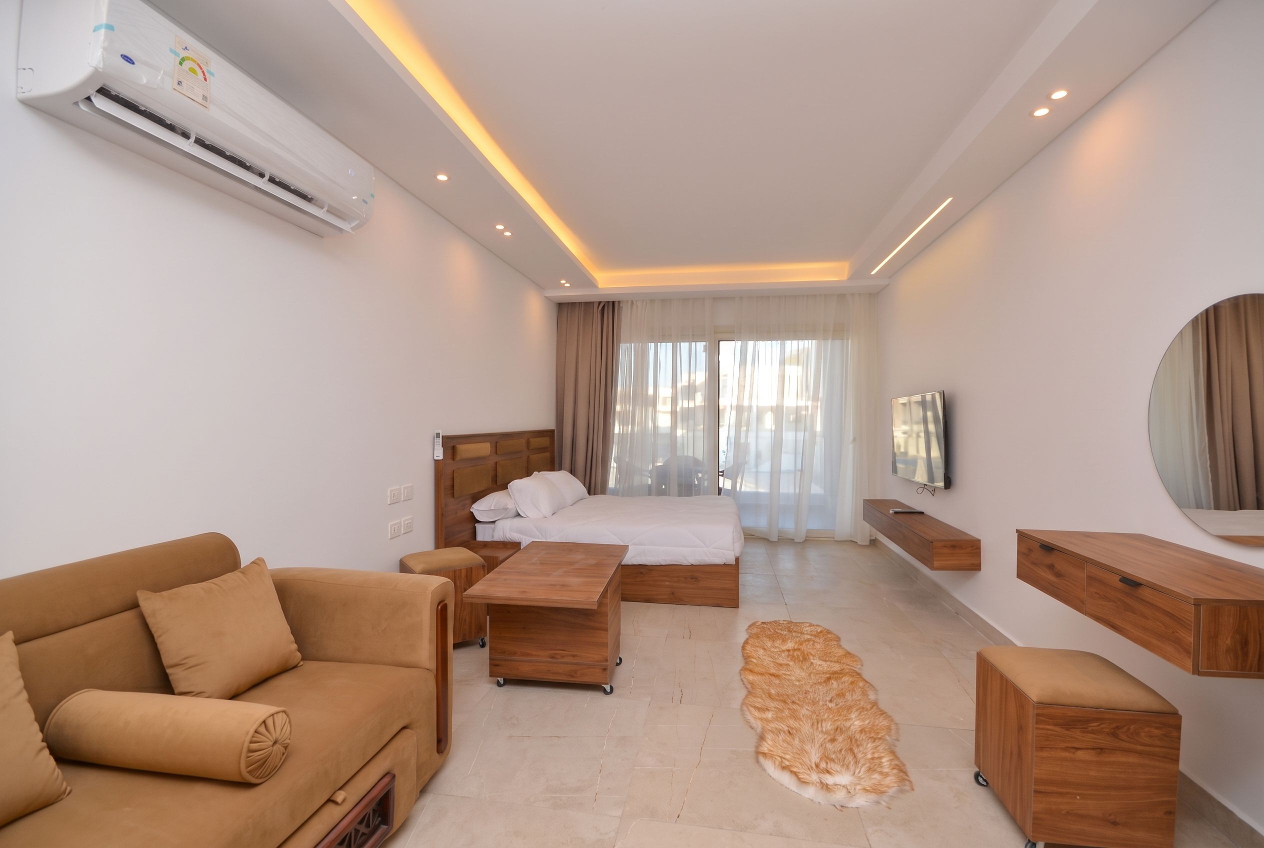 Ein modernes Hotelzimmer mit Bett, Sofa, Fernseher und einem kleinen Teppich.