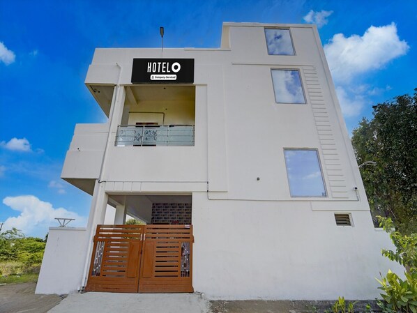 A modern hotel building with a sign reading 'HOTELO' and a company-serviced logo.