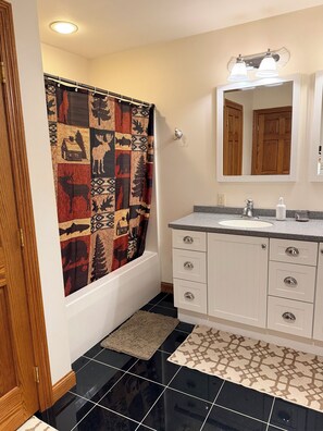 A bathroom with a white vanity, a mirror, a shower curtain with a deer pattern, and a black tiled floor. - Pet-Friendly 6BR Retreat on 14 Acres, Sleeps 12, Near Grand Rapids MN (Grand Rapids)