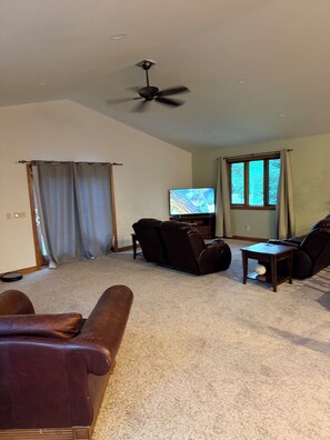 A living room with a ceiling fan, a television, and a brown leather sofa. - Pet-Friendly 6BR Retreat on 14 Acres, Sleeps 12, Near Grand Rapids MN (Grand Rapids)