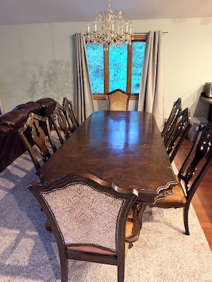 A dining room with a large wooden table, ornate chairs, a chandelier, and a view through a window with curtains. - Pet-Friendly 6BR Retreat on 14 Acres, Sleeps 12, Near Grand Rapids MN (Grand Rapids)