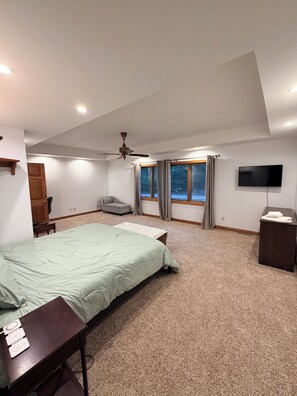 Un dormitorio con cama, escritorio, silla, televisor y ventana con cortinas.