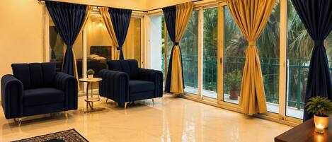 A modern living room with two sofas, a small round table, and a large window with curtains.
