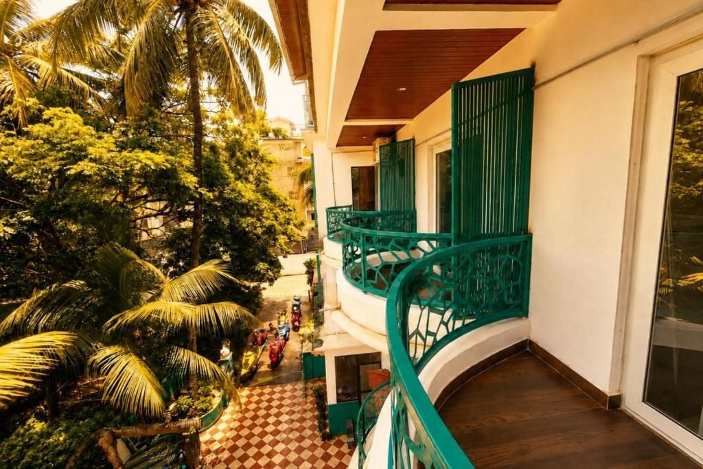 A multi-level building with a green balcony railing, a checkered floor pattern, and lush greenery.