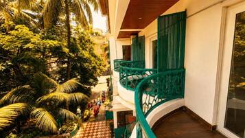 A multi-level building with a green balcony railing, a checkered floor pattern, and lush greenery.