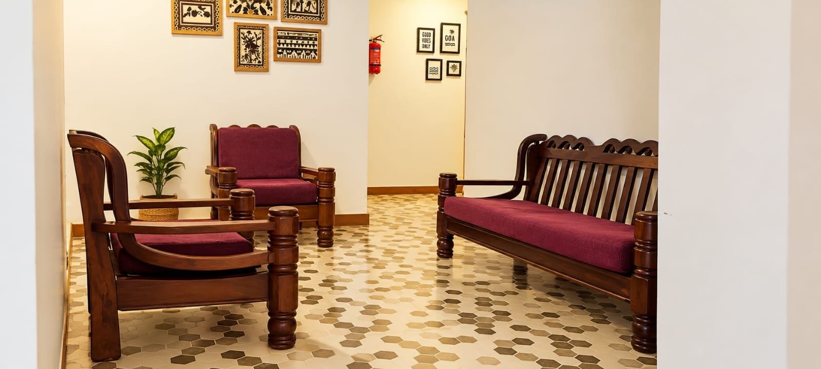 A lobby with a wooden bench, a wooden chair, and a potted plant.