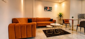 A modern living room with a sectional sofa, a round coffee table, and two chairs. - Mogachi Casa Goa Beach Stay (Calangute)