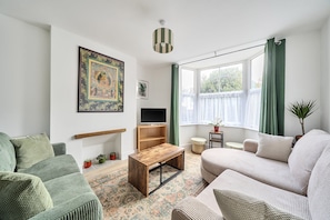 Ein Wohnzimmer mit einer Couch, einem Couchtisch, einem Fernseher und einem Gemälde an der Wand.