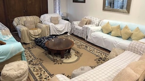 Ein Wohnzimmer mit einer Couch, Sesseln, einem Couchtisch und einem gemusterten Teppich.