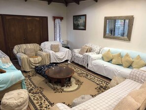Ein Wohnzimmer mit einer Couch, Sesseln, einem Couchtisch und einem gemusterten Teppich.