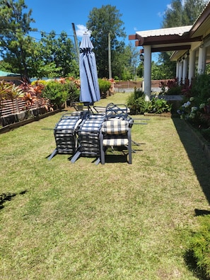 A patio area with outdoor furniture, including chairs and a table, under a covered umbrella.