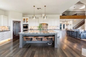 Una cocina amplia con una isla central, suelo de madera e iluminación colgante.