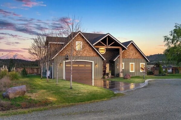 A two-story house with a garage, a stone exterior, and a driveway.