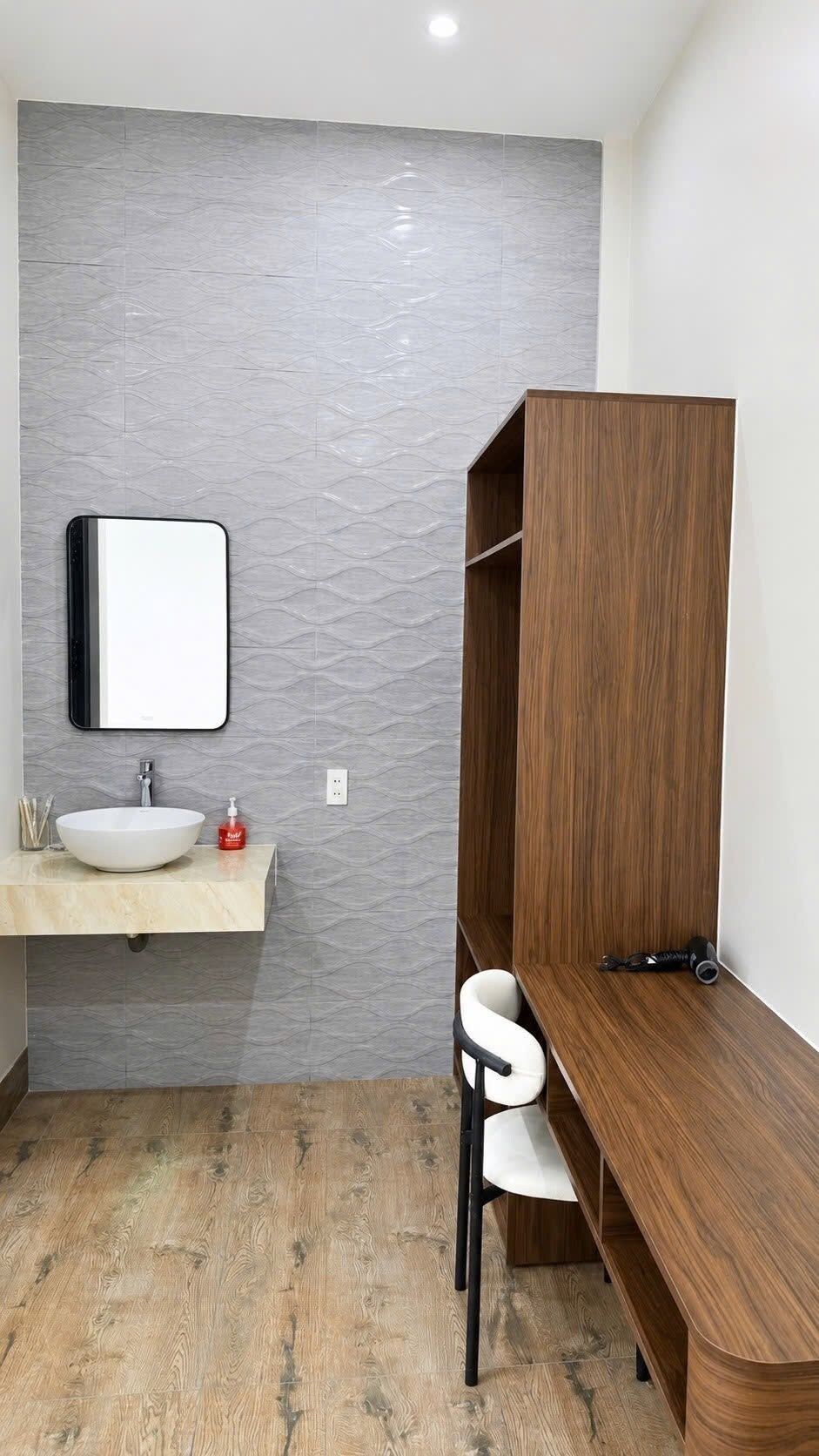 A bathroom with a vanity, a mirror, a sink, and a wooden bench.