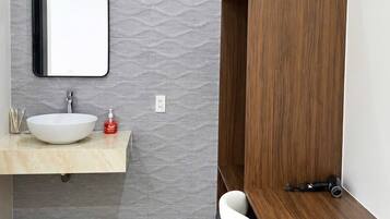 A bathroom with a vanity, a mirror, a sink, and a wooden bench.