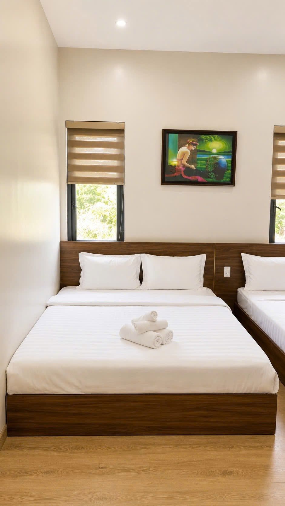 Una camera d'hotel con un letto grande, due comodini, un quadro appeso al muro e una finestra con persiane.