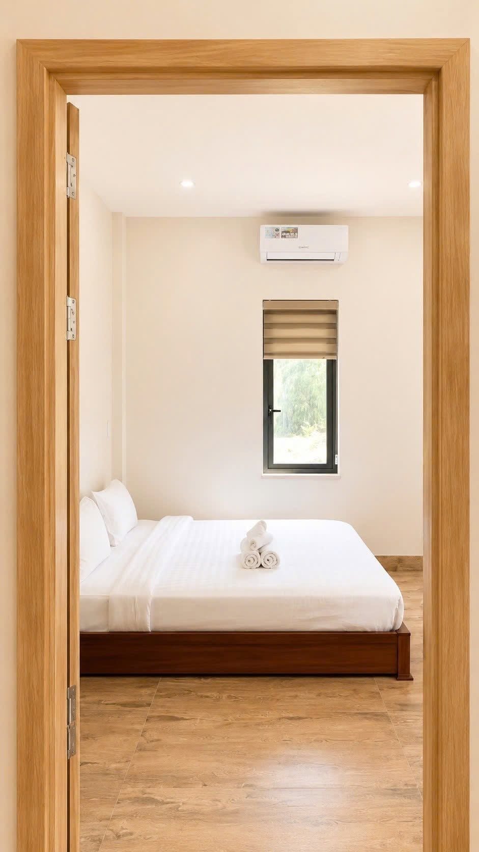 A bedroom with a bed, a window with blinds, and an air conditioning unit.