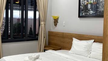 Ein Hotelzimmer mit Bett, Vorhängen, einer Wandleuchte und einem Gemälde.