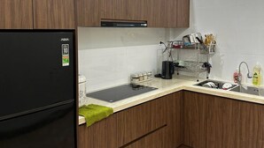 Una cocina moderna con armarios de madera, un refrigerador negro y un lavamanos de acero inoxidable.