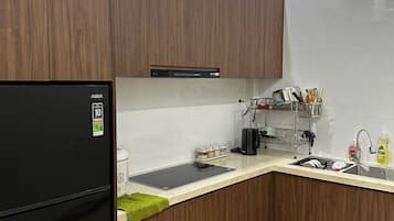 Une cuisine moderne avec des meubles en bois, un réfrigérateur noir et un évier en acier inoxydable.