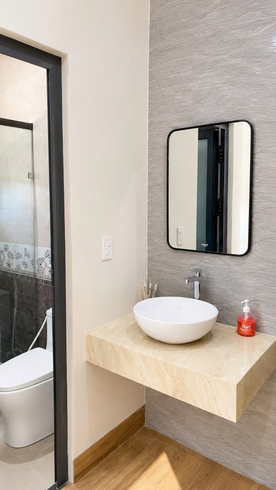 Un bagno con un lavandino bianco, uno specchio e un water.