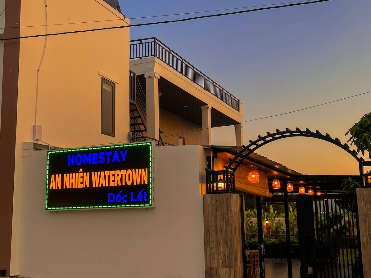 A hotel entrance with a neon sign, a covered walkway, and a gated entrance.