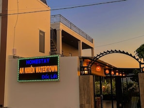 Ein Hotel Eingang mit einer Neonreklame, einem überdachten Gang und einem verschlossenen Tor.