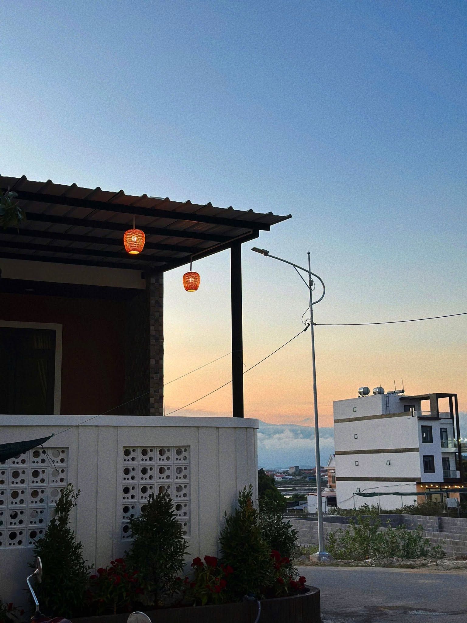 Un edificio con techo inclinado, toldo metálico y pared con aberturas circulares.