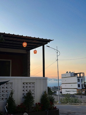 A building with a sloped roof, a metal awning, and a wall with circular cutouts. - Anna Home Doc Let (Dong Ninh Hoa)