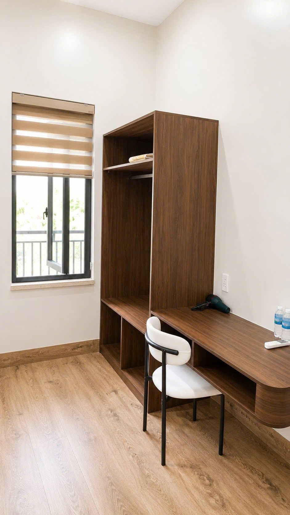 A room with a wooden desk, a white chair, and a wardrobe.