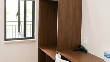 A room with a wooden desk, a white chair, and a wardrobe.