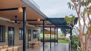 An outdoor patio area with a covered seating area, a dining table, and chairs. - Anna Home Doc Let (Dong Ninh Hoa)